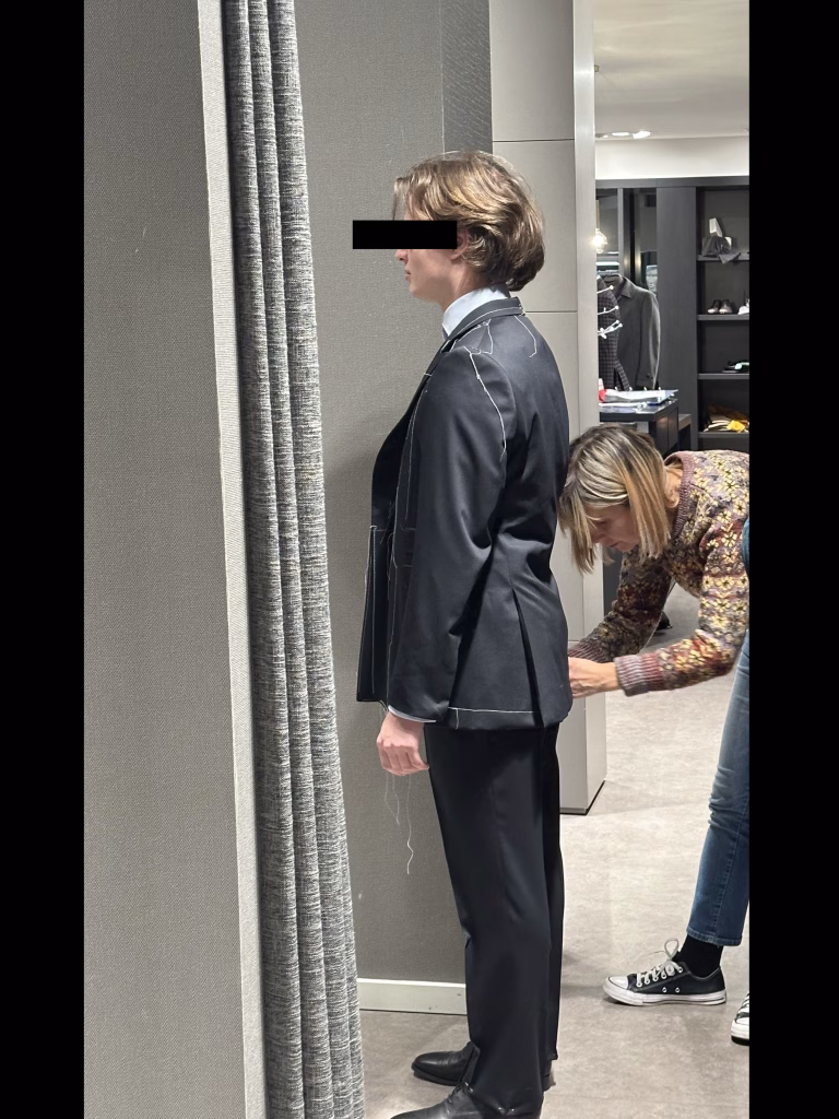Costureira a ajustar as costas de um casaco de fato clássico da Crialme, visto de lado.