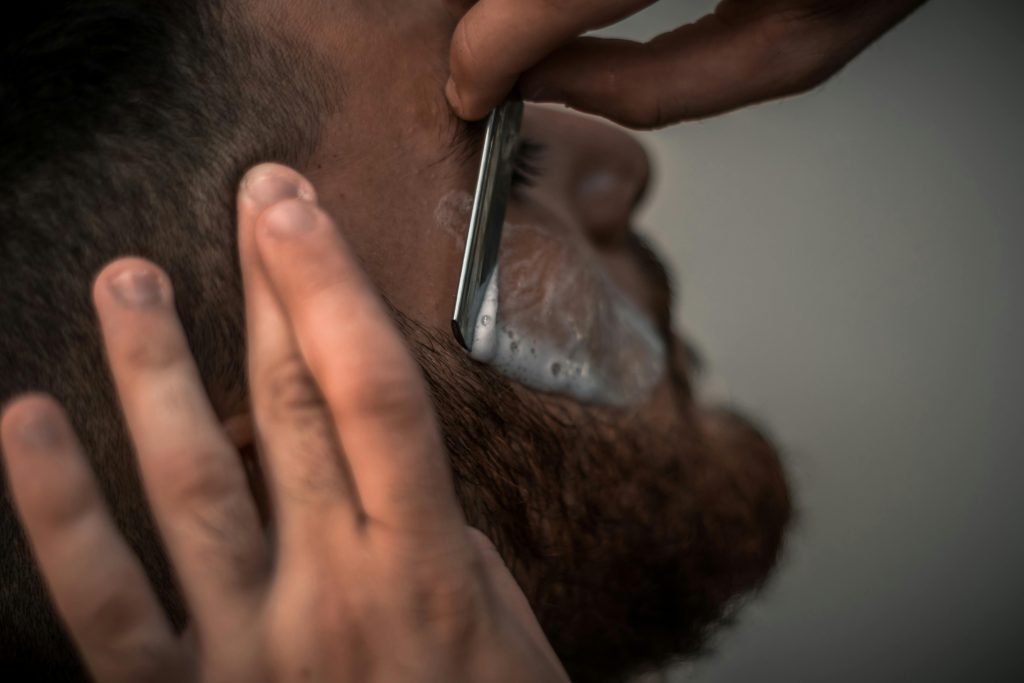 Homem a fazer a barba com uma navalha.