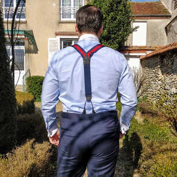 Homem a usar suspensórios por cima de uma camisa, visto de costas.