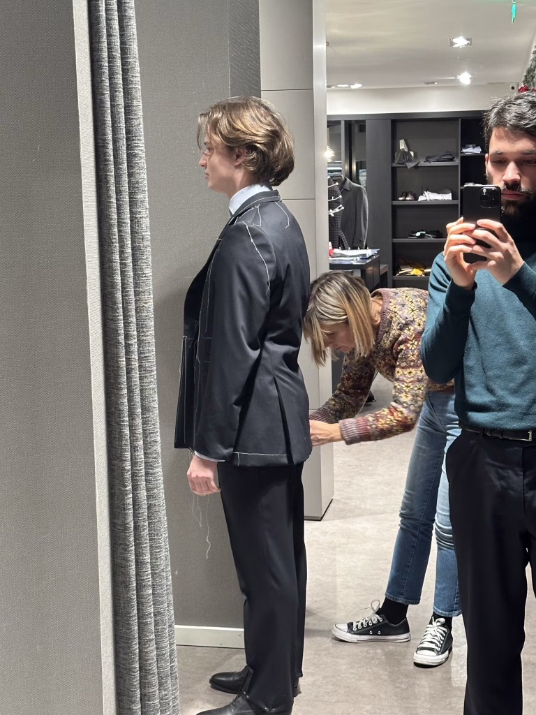 Costureira a ajustar as costas de um casaco de fato clássico da Crialme, visto de lado.