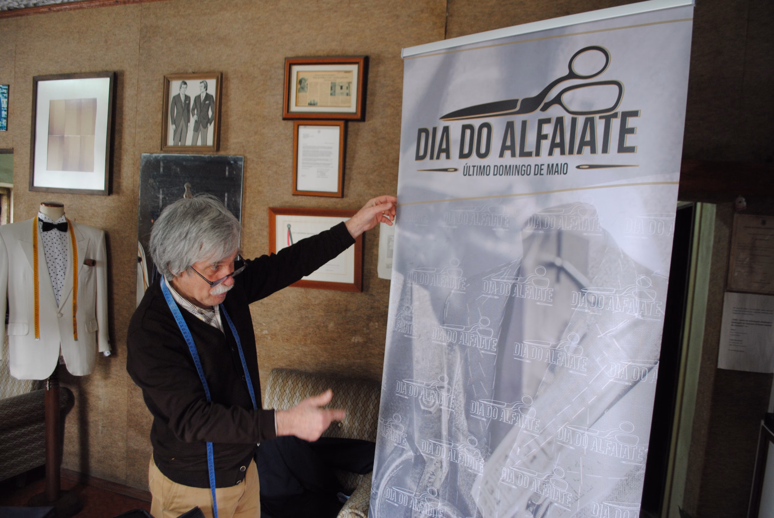 Mestre alfaiate Sr. Néu da Alfaiataria Moderna em Ponte da Barca em primeira prova, a mostrar o cartaz do dia do alfaiate, visto que foi um dos seus organizadores originais.