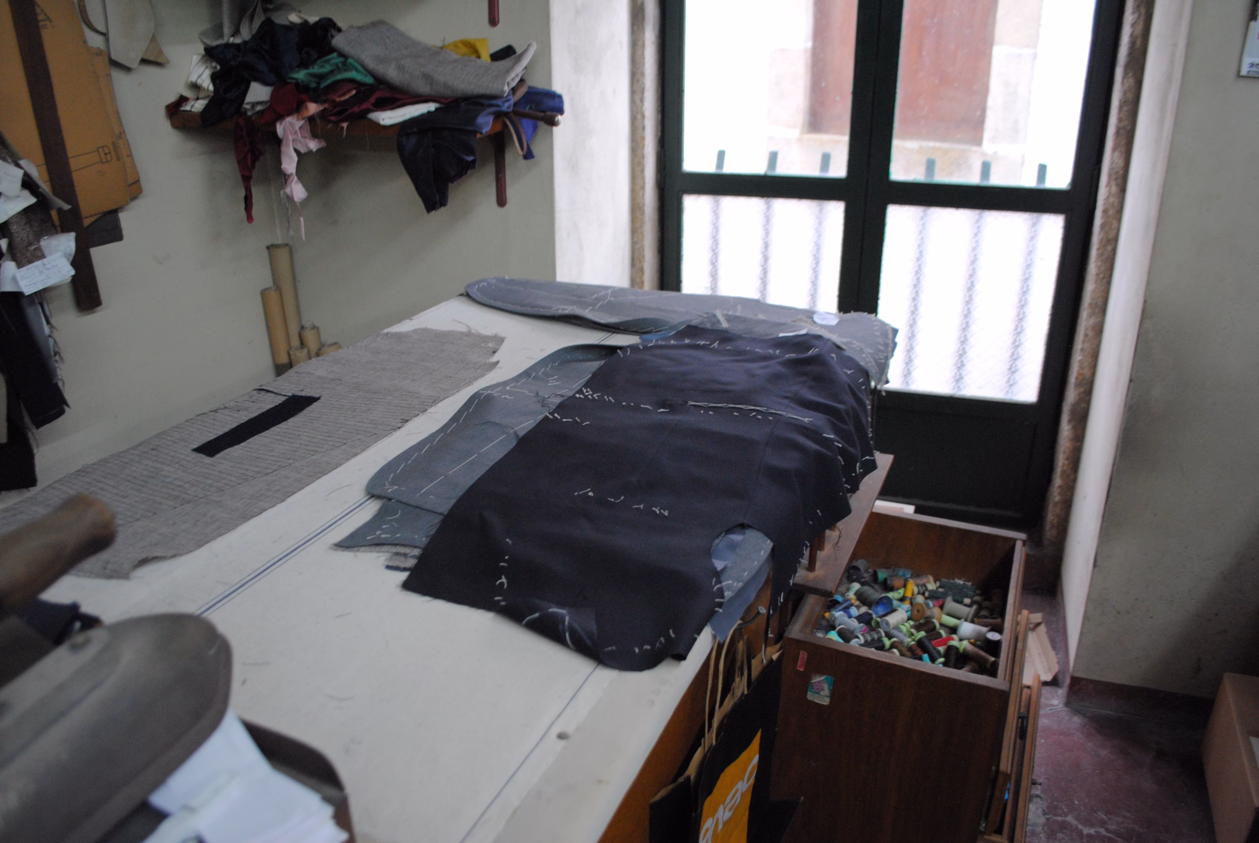 Interior da oficina da Alfaiataria Modernam com partes do casaco já cortadas e prontas a serem cosidas.